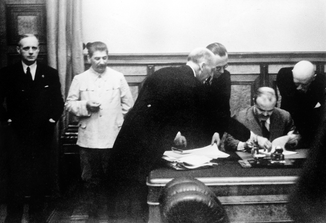 Ministr zahraničí SSSR Vjačeslav Molotov při podpisu sovětsko-německé smlouvy o neútočení. Vlevo stojí německý ministr zahraničí Joachim von Ribbentrop a Stalin.