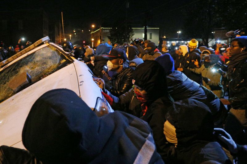 Rozvášněný dav převrací policejní auto před radnicí ve Fergusonu. Rozvášněný dav převrací policejní auto před radnicí ve Fergusonu.