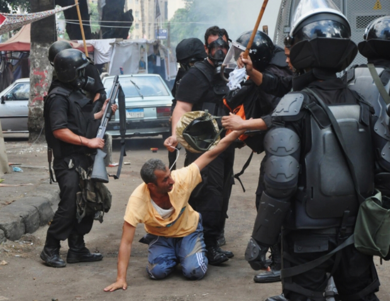 Policisté zadržují stoupence svrženého prezidenta Mursího při demonstraci 14. srpna 2014.