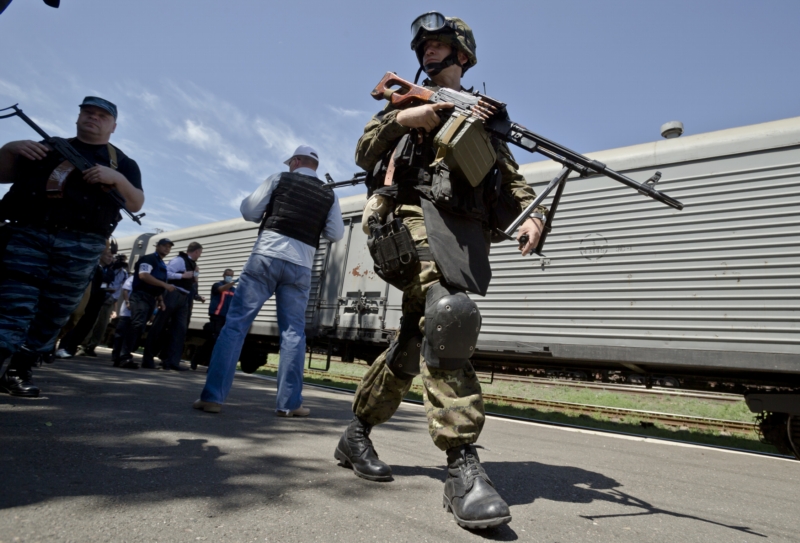 Na snímku prochází proruský separatista, zatímco pozorovatelé OBSE zkoumají vlak se zmraženými mrtvými těly obětí pádu letu MH17 na východní Ukrajině. Ilustrační foto.