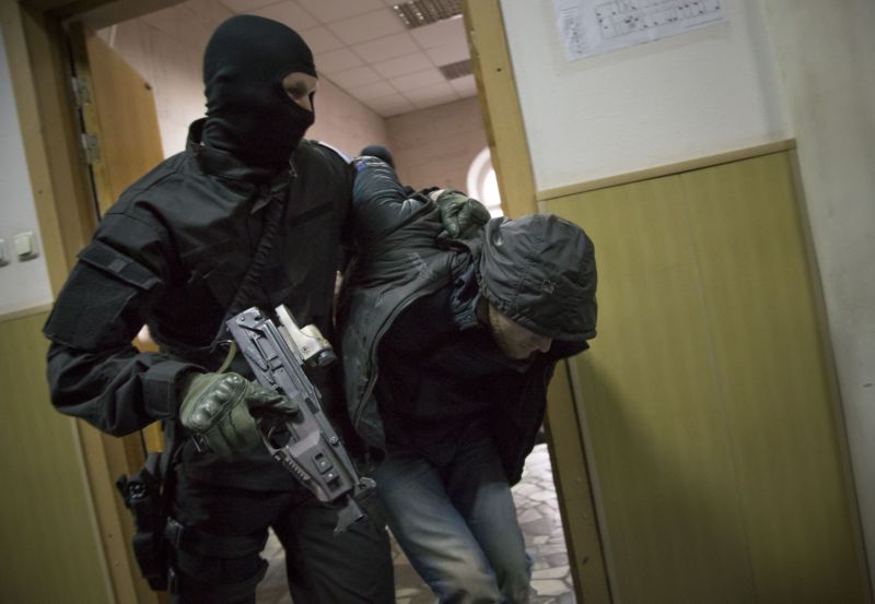 Jeden ze zadržených v doprovodu policisty na chodbě soudu v Moskvě. Jeden ze zadržených v doprovodu policisty na chodbě soudu v Moskvě.