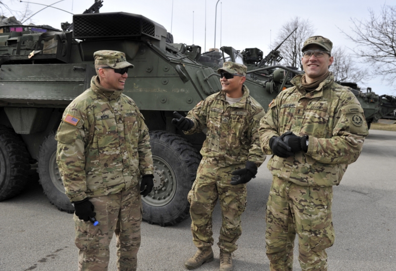 Američtí vojáci stojí před transportérem Stryker.