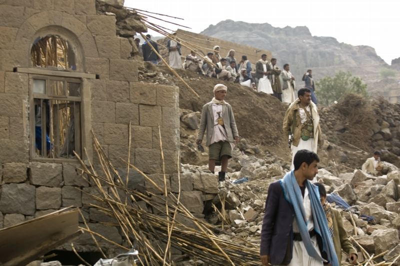 Jemenci v troskách vesnice, která byla zničena bombardováním arabské koalice.