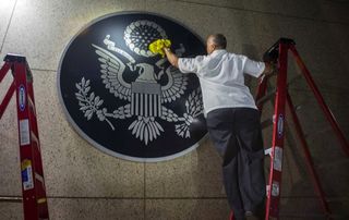Zaměstnanec čiští Velkou pečeť Spojených států v nově otevřeném americkém velvyslanectví v Havaně.