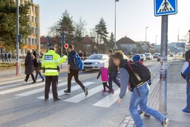 Strážník hlídá přechod, přes který chodí děti do školy.