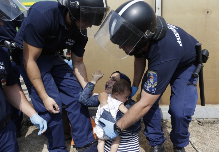 Syrská matka s dítětem a kolem ní maďarští policisté.