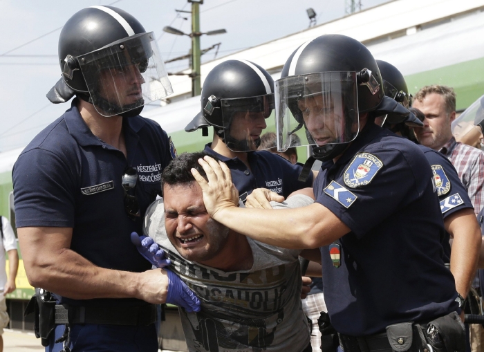 Migrant v sevření maďarských policistů.
