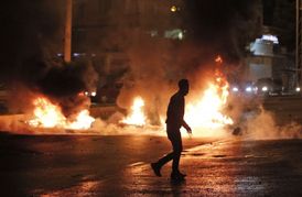 Maskovaný demonstrant běží kolem odpadků, které zapálili příznivci pro-kurdské demokratické lidové strany (HDP) na protest proti výsledkům předčasných parlamentních voleb. Diyarbakir, jihovýchodní v Turecko.