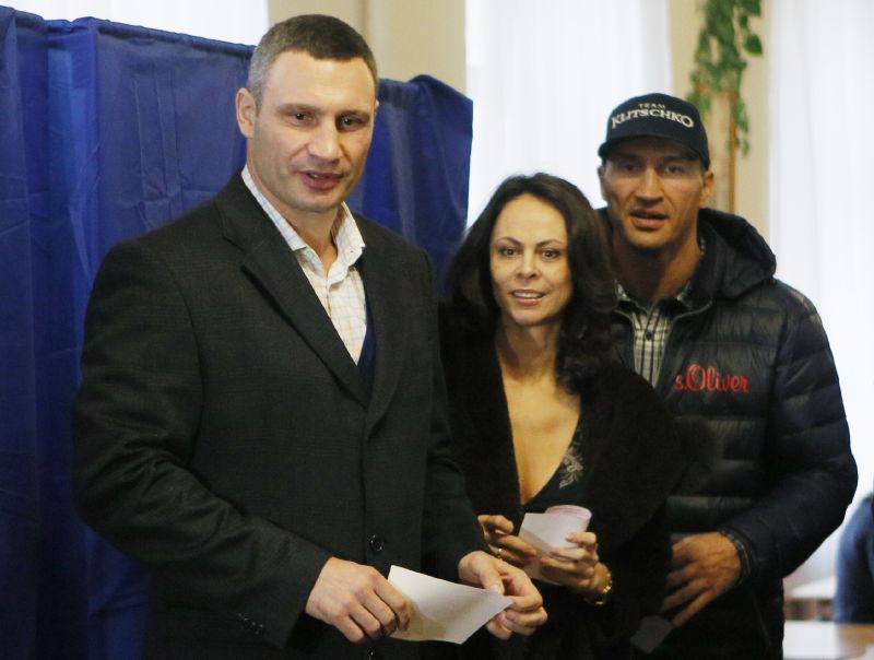 Vitalij Kličko (vlevo) na dnešních volbách za podpory své ženy a bratra Vladimíra.