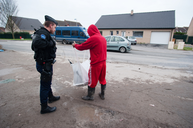 Uprchlík kontrolován policistou (ilustrační foto).