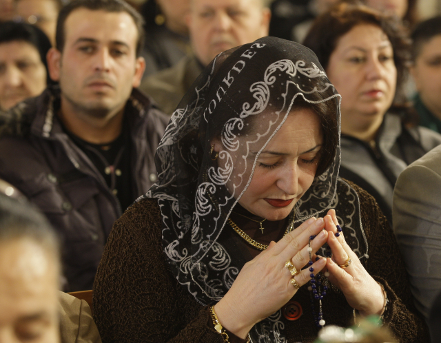 Iráčtí křesťané v kostele v Iráku. Při vstupu je kontrolují ozbrojené jednotky (ilustrační foto).