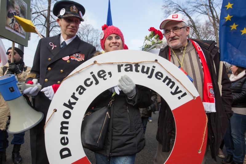 Demonstrující ve Varšavě nesou záchranný kruh s nápisem Zachráníme demokracii. Demonstrující ve Varšavě nesou záchranný kruh s nápisem Zachráníme demokracii.
