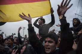 Projevy migrantů v táboře Idomeni, zpívají písně věnované německé kancléřce Angele Merkelové a vystavují německou vlajku, vše se děje během summitu o imigrační krizi vedoucích představitelů EU s Tureckem v Bruselu.