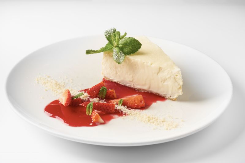 Cheesecake z bílé čokolády na korpusu z pražených oříšků, datlí a rebarborovým kompotem.