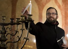 Vrchní pražský rabín David Peter na snímku zapaluje v Jeruzalémské synagoze v předvečer osmidenního svátku světel první svíci na chanukovém svícnu.