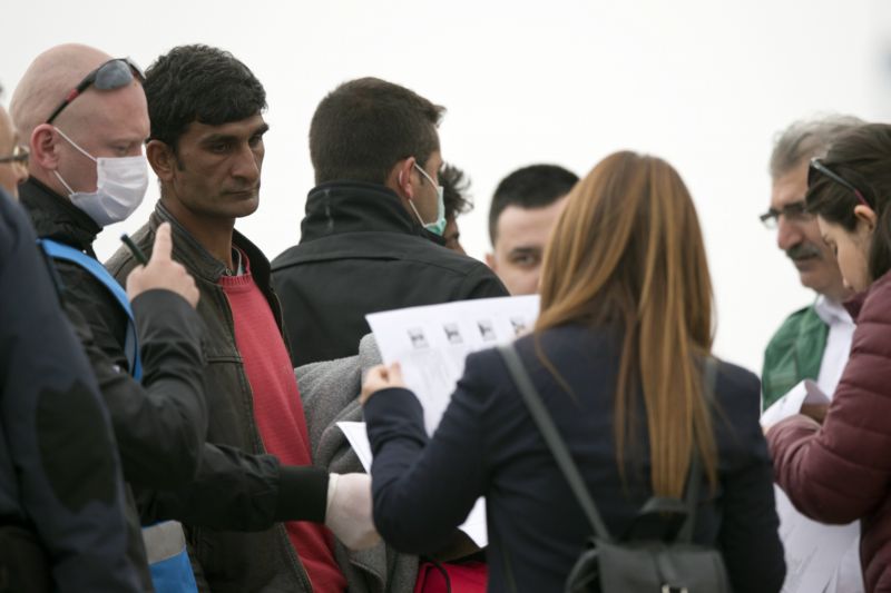 Pracovníci agentury Frontex a zaměstnanci tureckého ministerstva vnitra kontrolují doklady pákistánského migranta (druhý zleva).
