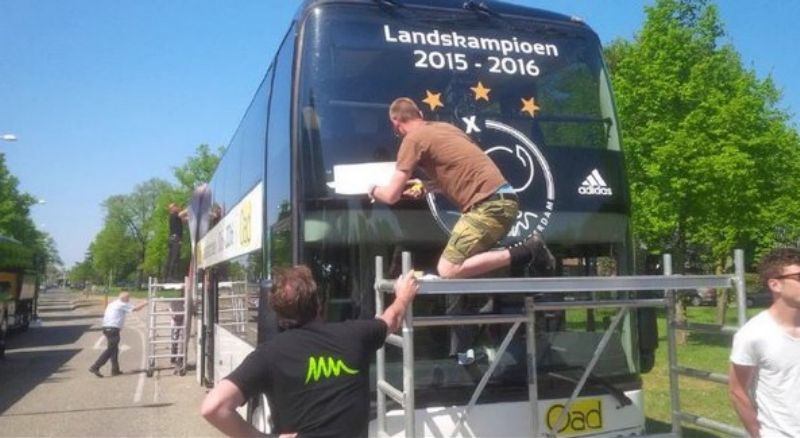 Klubový autobus Ajaxu už zdobily mistrovské nápisy. Musely zas dolů.