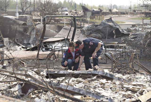 Kanadský premiér Justin Trudeau (vlevo) a šéf požárníků Darby Allen prohlížejí devastaci po požáru ve městě Fort McMurray.