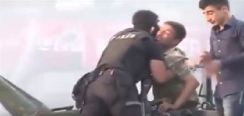 Policista vytahuje vojáka do bezpečí před davem.