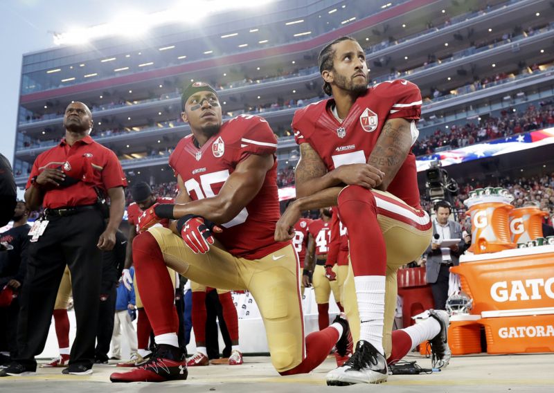 Kaepernick a jeho spoluhráč Reid na kolenou při americké hymně.