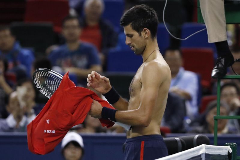 Tenista Novak Djokovič si mění tričko, které na sobě rozerval vzteky.
