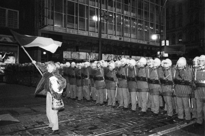 Demonstrant s vlajkou před policejním kordonem na Národní třídě 17. listopadu 1989.