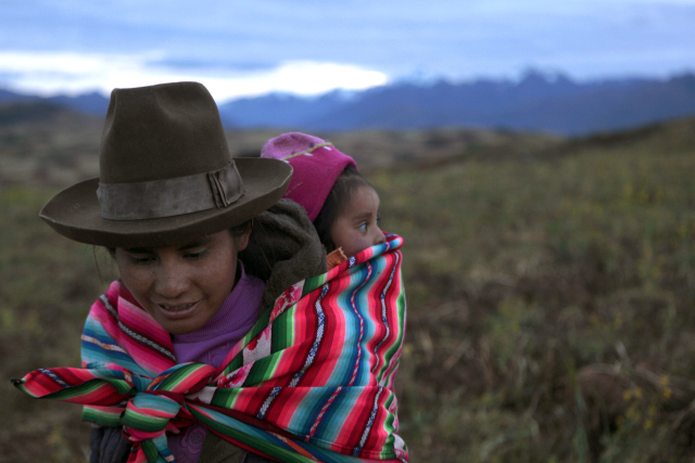 Domorodá žena nese dítě na zádech ve městě Cuzco na jihu Peru v Andách.