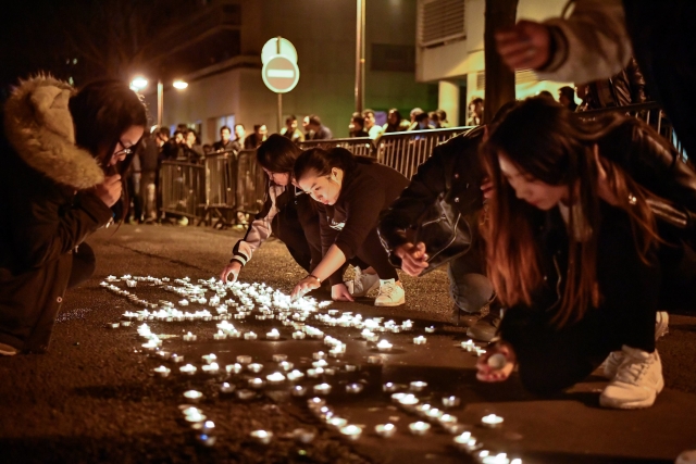 Demonstranti z čínské komunity skládají v pařížské ulici svíčky do nápisu violence (v překladu znamenajícího násilí).