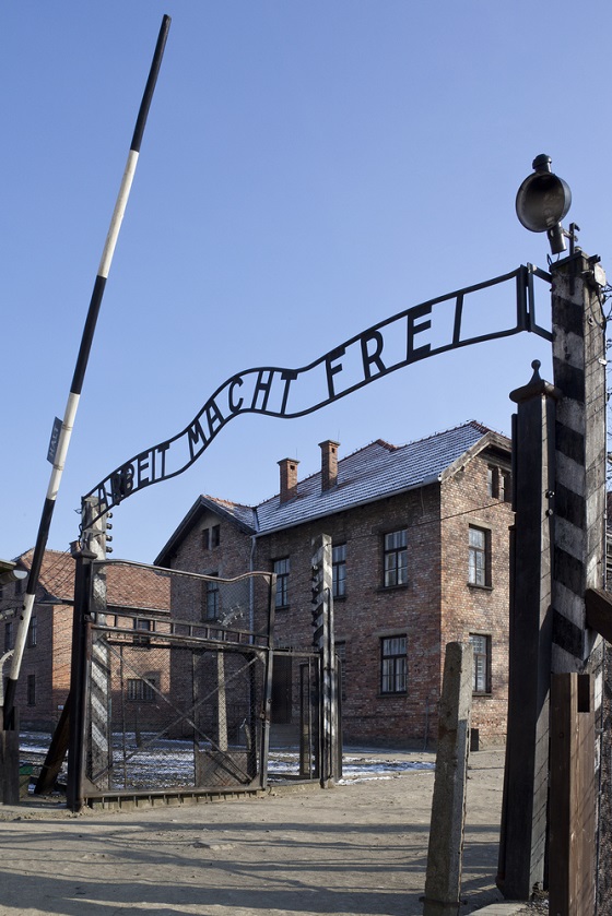 Brána koncentračního tábora v Osvětimi s nápisem Arbeit macht frei.
