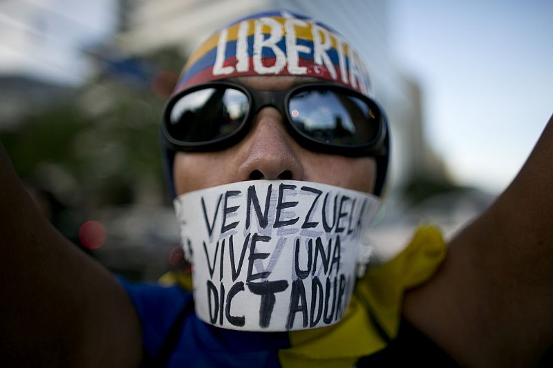 Demonstrující proti vládě ve venezuelském Caracasu. (Na nápisu stojí: "Venezuela žije v diktatuře").