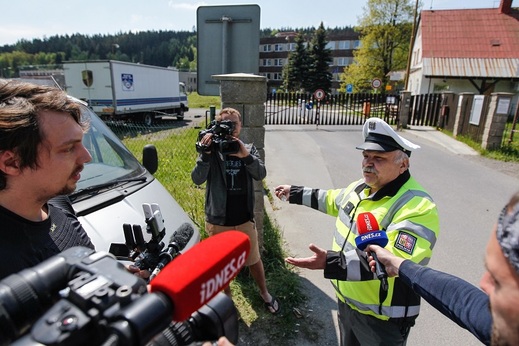 Na snímku dopravní policista řeší parkování novinářských aut mimo vyhrazená místa před věznicí.