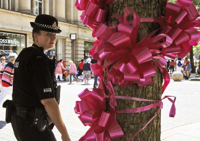 Policejní hlídka prochází kolem růžové stuhy (hold Manchesteru).