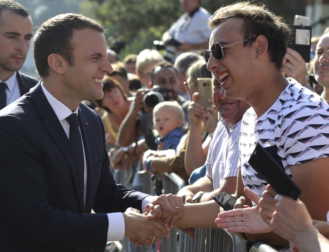 Prezident Emmanuel Macron si potřásá rukou s voličem.