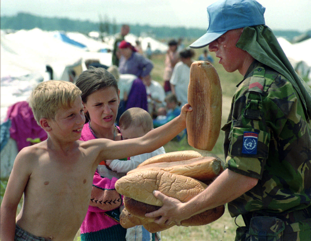 Uprchlíci ze Srebrenice. Nizozemští příslušníci UNPROFOR rozdávají chléb bosenským dětem na letišti v Tuzle. Červenec 1995.