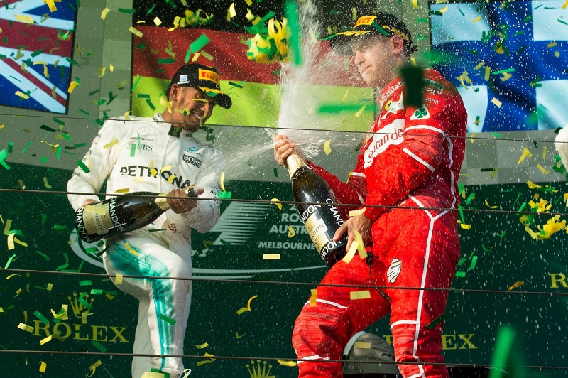 Brit Lewis Hamilton (zleva) kropí šampaňským vítěze VC Austrálie Sebastiana Vettela z Německa.