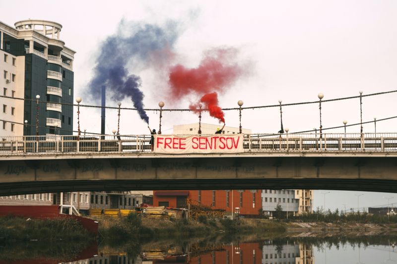 Členky skupiny Pussy Riot držící světlice a banner na mostě poblíž věznice v Yakutsku.