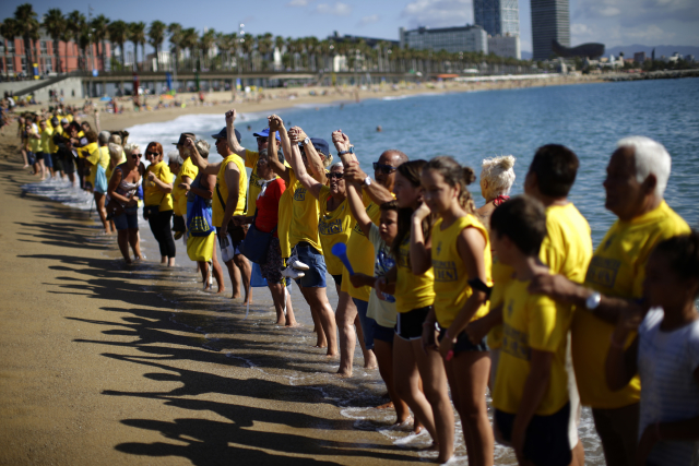 Lidé protestující na barcelonské pláži proti masovému turismu.