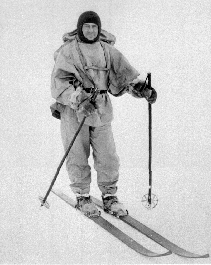 Robert Falcon Scott, anglický polárník, který 18.ledna 1912 jako druhý dosáhl jižního pólu (celá postava na lyžích).