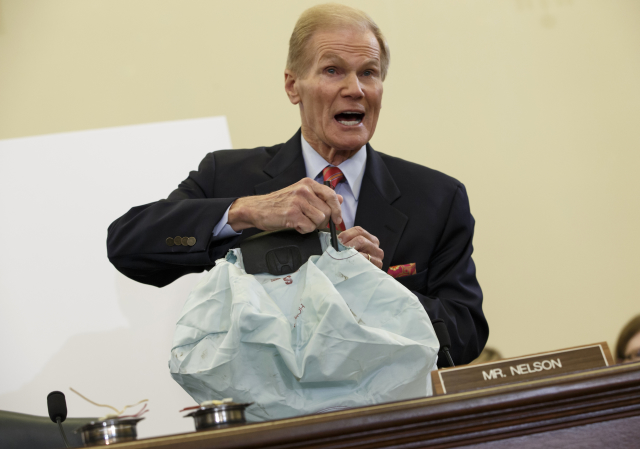 Senátor obchodního výboru USA Bill Nelson ukazuje vadný airbag společnosti Takata.