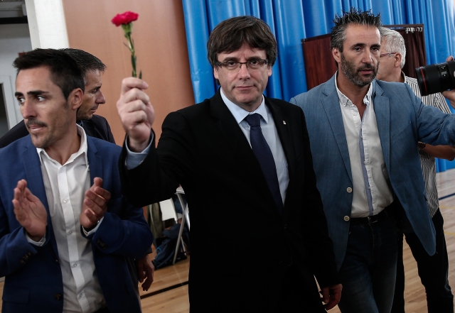 Katalánský premiér Carles Puigdemont (s květinou) v jedné z hlasovacích místností.