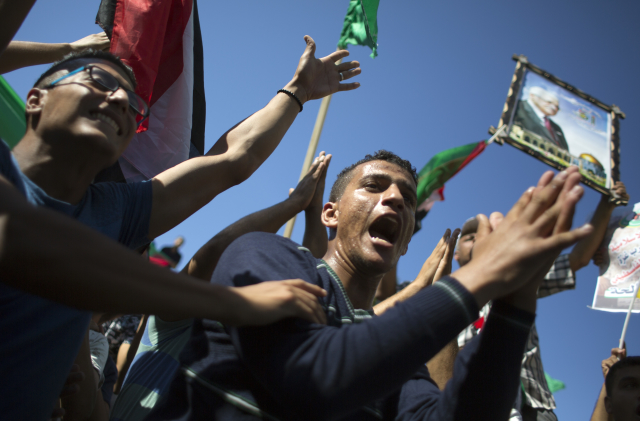 Palestinci, kteří drží plakát palestinského prezidenta Mahmúda Abbáse, oslavují podepsání dohody o usmíření mezi Hamásem a Fatahem v Egyptě.