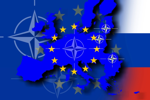 Symbol EU na pozadí vlajky NATO (vlevo) a ruské vlajky.
