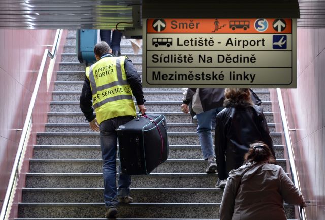 Nosiči pomáhají turistům s kufry na zastávce metra Veleslavín. 