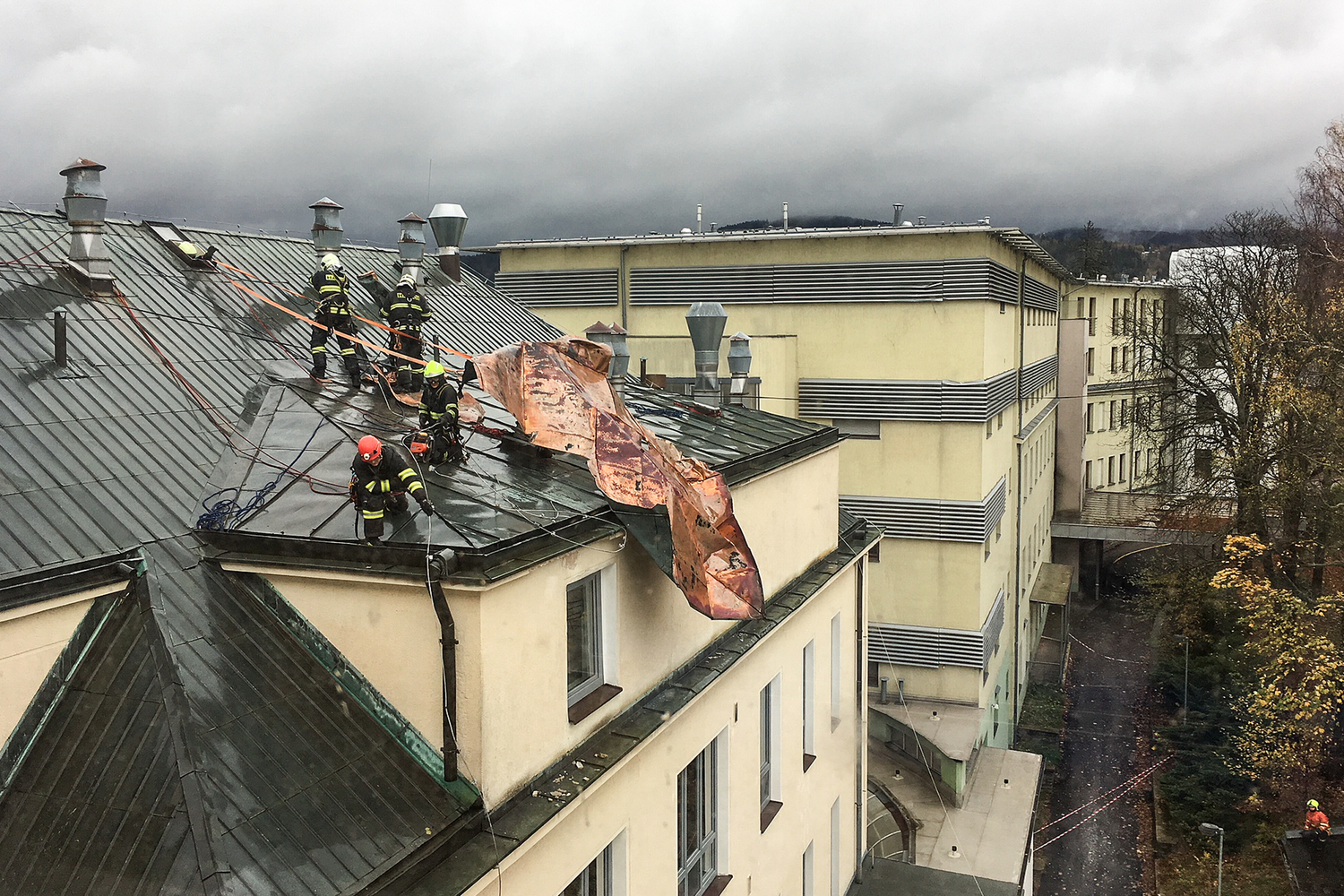 Hasiči odstraňují následky vichřice, jež poškodila střechu liberecké nemocnice.