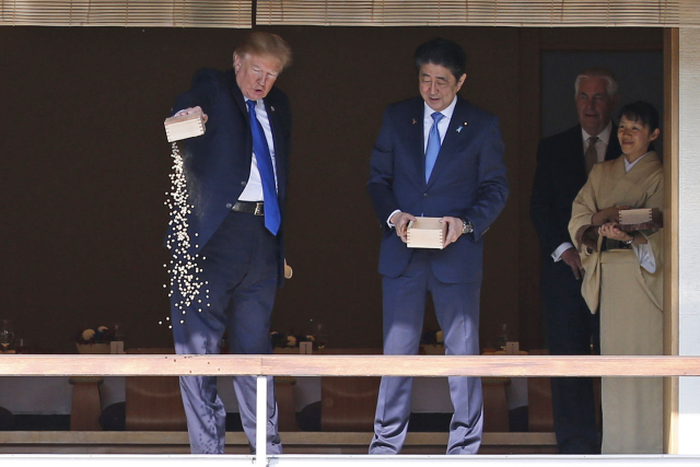 Donald Trump s japonským premiérem Šinzóem Abem krmí rybky.