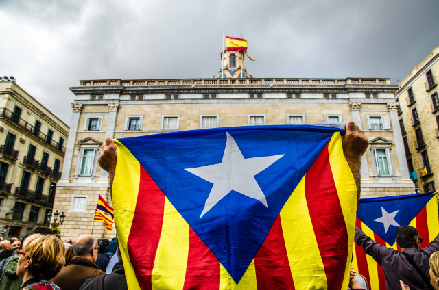 Muž s vlajkou Katalánska demonstruje za jeho nezávislost před palácem generála Catalunya.