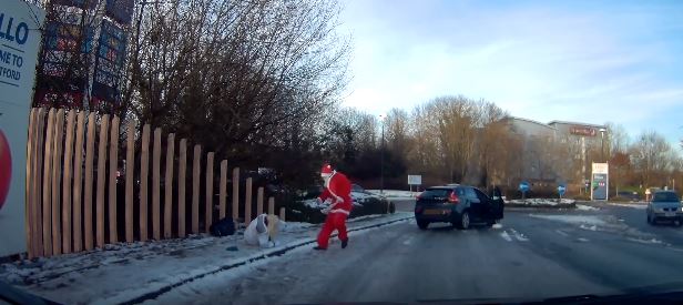 Santa Claus pomáhá ženě, která uklouzla na zledovatělém chodníku. Santa Claus pomáhá ženě, která uklouzla na zledovatělém chodníku.