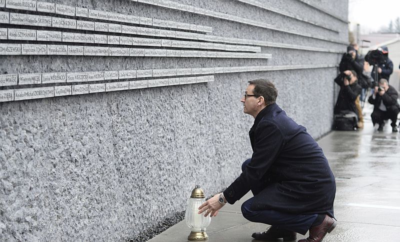 Polský premiér Mateusz Morawiecki zapaluje svíčku ve vsi Markowa.