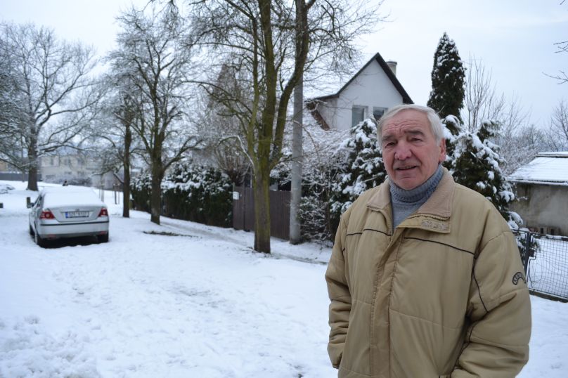 Miloslav Jiříček, soused tří zlínsikých obětí. V pozadí za ním osudový dům a automobil zřejmě zavražděné rodiny.