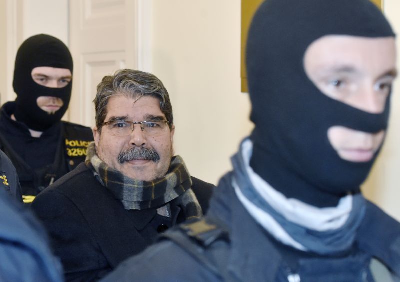 Policisté přivádějí zadrženého kurdského politika Sáliha Muslima k pražskému městskému soudu.